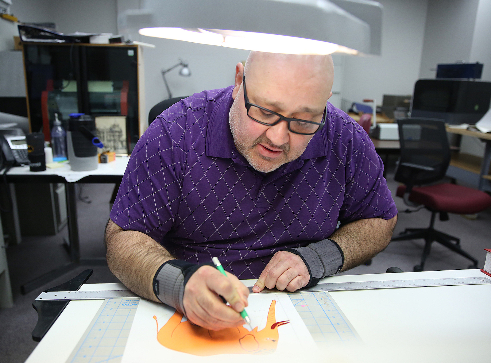 A Clovernook Center employee carefully produces a tactile graphic of an elephant by hand.