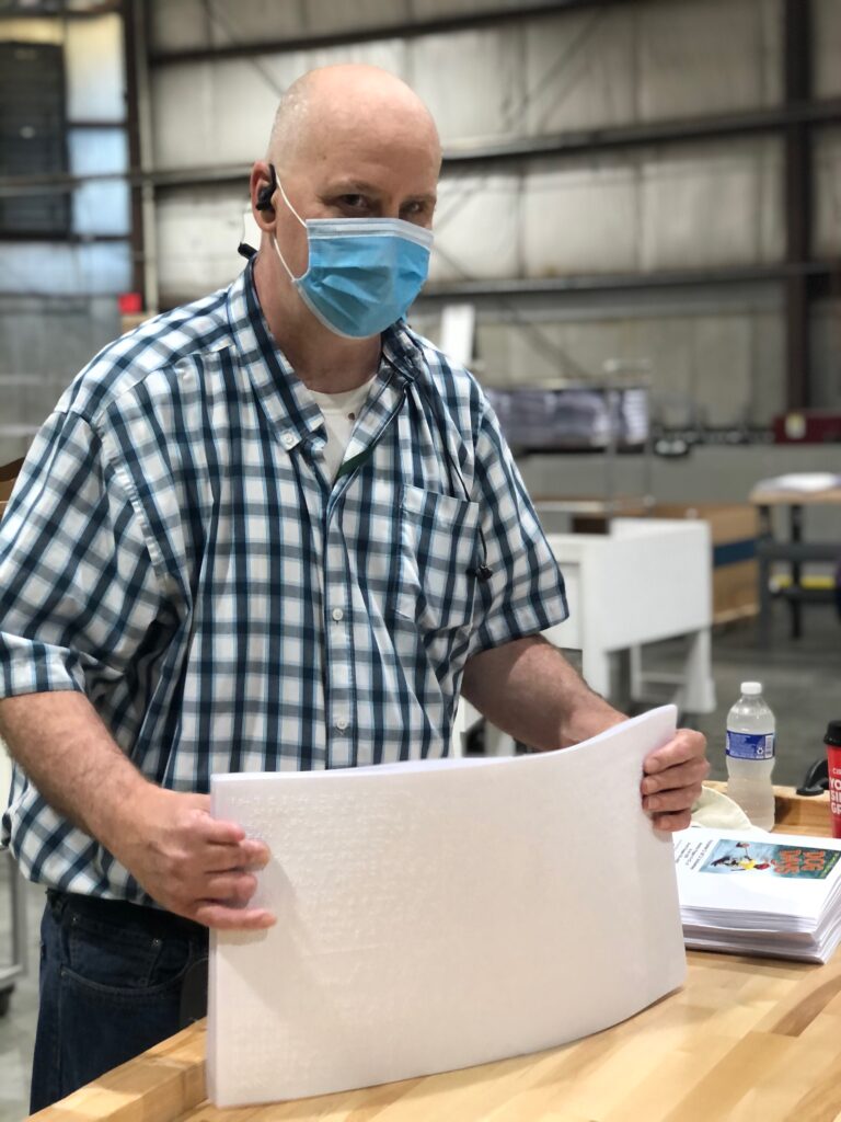 man in mask holding stack of papers