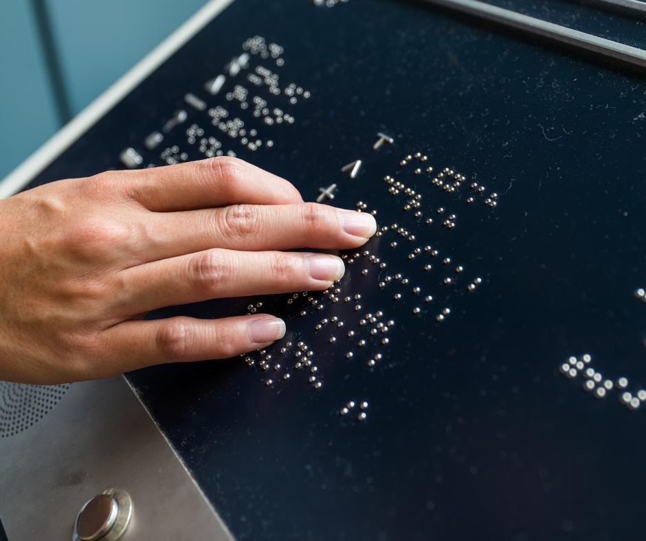 hand reading a black braille sign with the braille alphabet