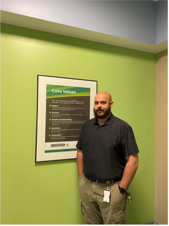 image of a bald white man standing in front of a green wall with his hands in his pockets
