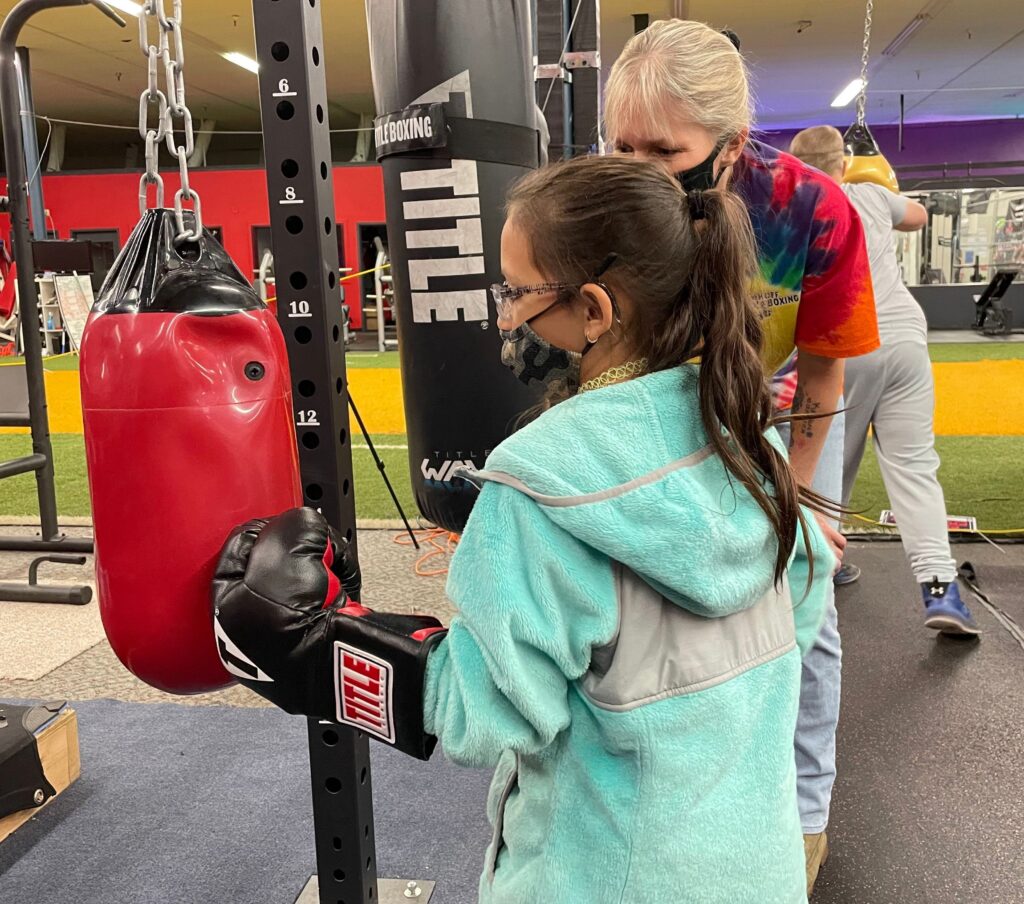 Image of Laylah hitting a boxing bag with her coach by her side