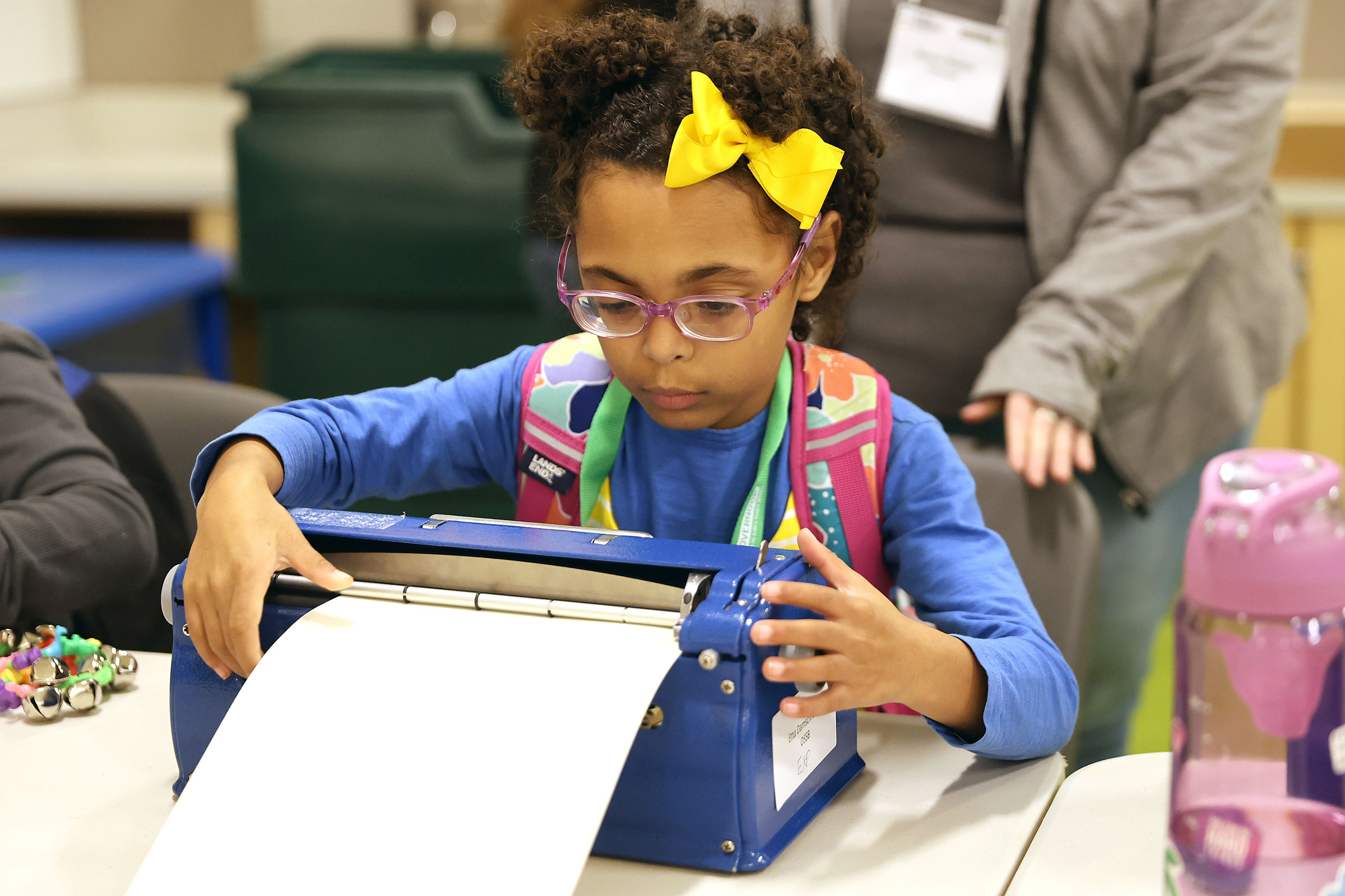A young girl wearing a bright, yellow bow types on a braille writing machine during the Ohio Regional Braille Challenge.