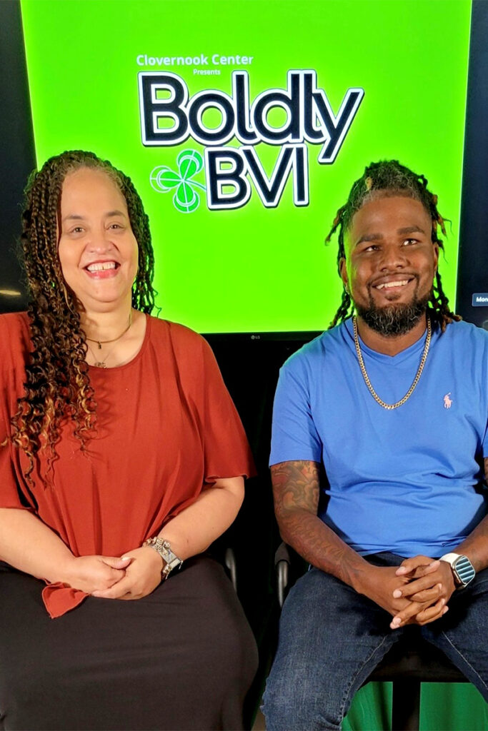 Hosts Stephanie Jones and Brian Anderson flash big smiles while sitting side-by-side. A monitor behind them features a green background with the words “Boldy BVI” and the Clovernook Center shamrock.