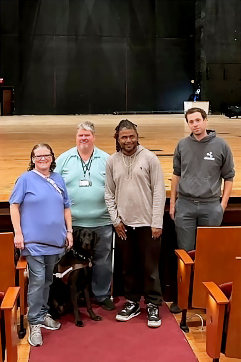 The Accessibility Audit team stands in front of a theater stage during a recent audit.