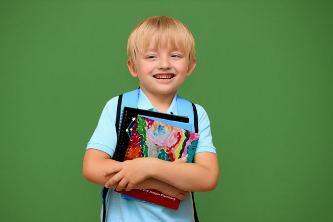 A young, smiling boy in a blue shirt hugs a stack of Clovernook books to his chest.