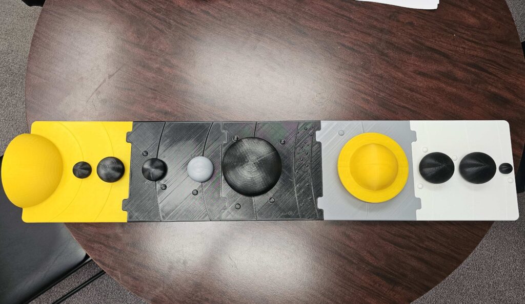 An image of a 3D printed solar system. The sun is on the left hand side and t he planets are in order.